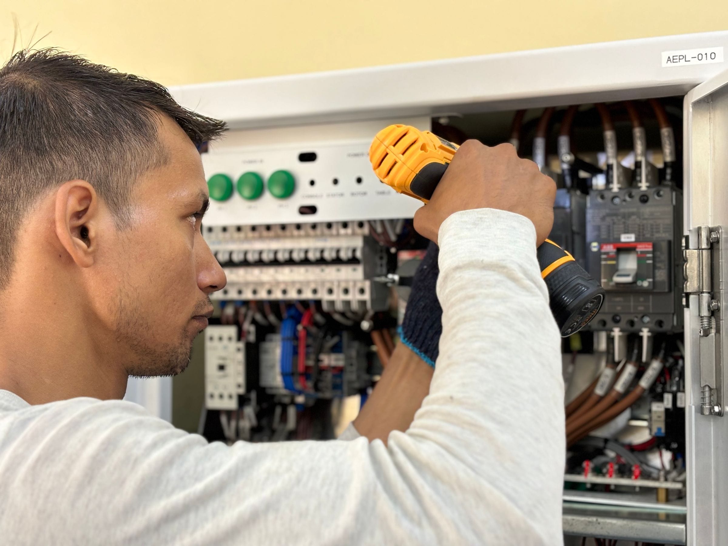 An electrician working inside a breaker panel