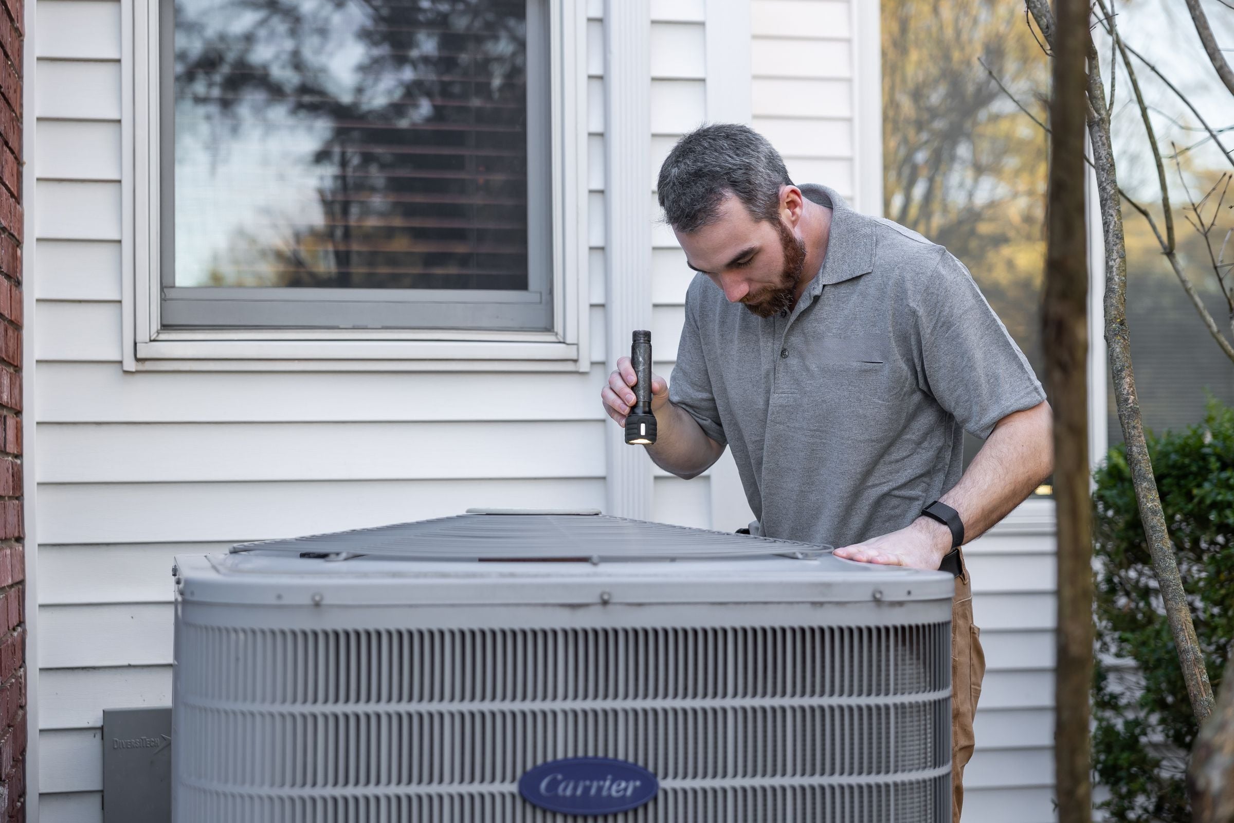 A technician checking an outdoor air conditioning unit